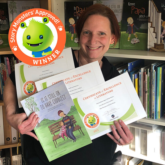 Author Elke Thompson holding her award-winning children's book 'Is it still ok to have cuddles?' and the Story Monsters Approved certificates in categories Picture Books, Family Matters and Health & Wellness.