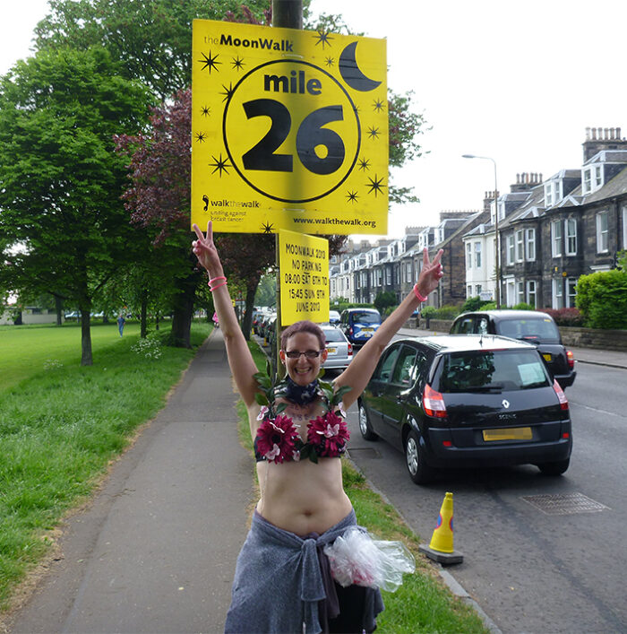 Elke in 2013 in front of the 26 mile sign at the Moonwalk marathon.